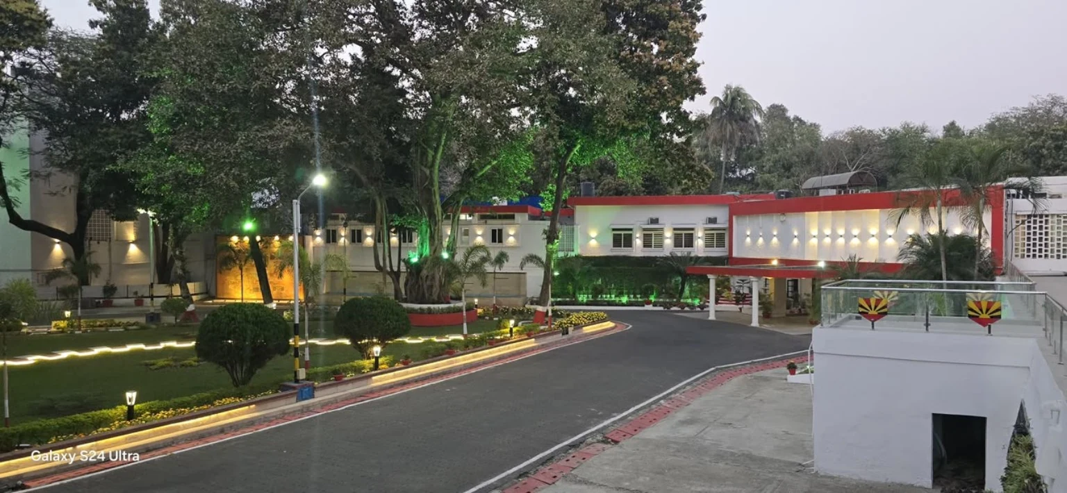 A road beside landscaped gardens with pathway lighting at dusk.