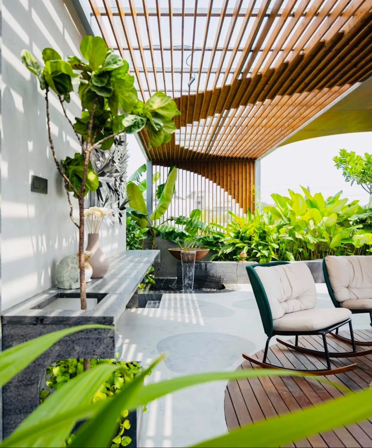 Green terrace beneath a timber-style pergola with outdoor seating